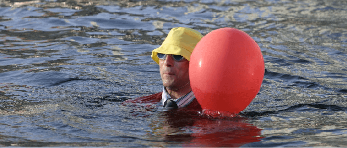 actor in the ocean with yellow hat and red ballon