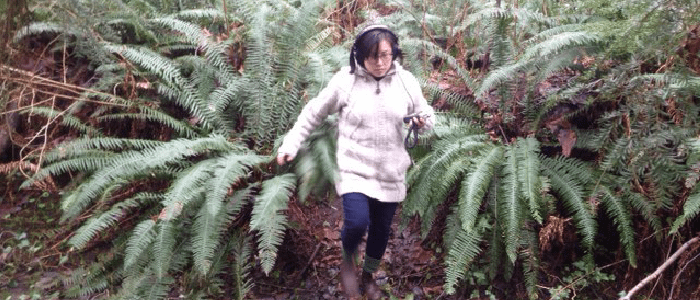 a women running through big ferns listening to the nature around her