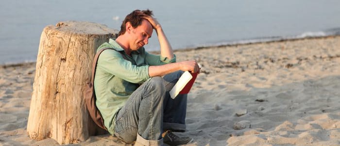 a distraught man siting on a beach