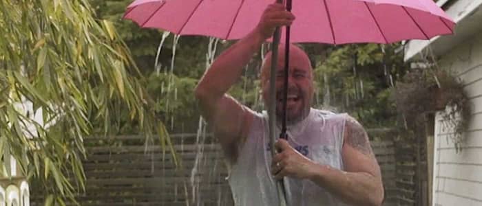 a man standing under an umbrella getting wet